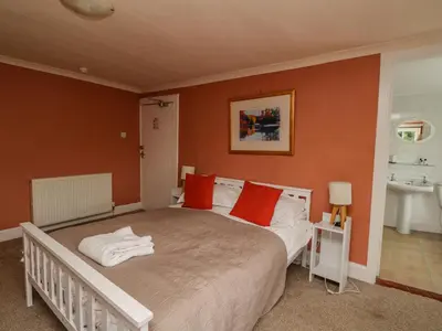 a bedroom with a large bed with red pillows at The House at Bridge of Lochay in Killin