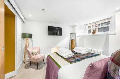 a bedroom with a bed and a chair and a tv at RÌGH Properties - Luxury West End Artisan Apartment in Edinburgh