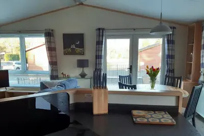 a kitchen and living room with a table and chairs at Sycamore Lodge Auchterarder in Auchterarder