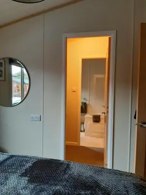 a bedroom with a bed and a mirror and a bathroom at Sycamore Lodge Auchterarder in Auchterarder
