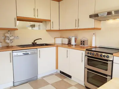a kitchen with white cabinets and a stove top oven at The Old Post Office On Loch Tay in Stron-fearnan