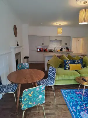 a living room with a green couch and a table and chairs at Slateford House 1770 Luxury Aparthotel by The House of Danu in Edinburgh