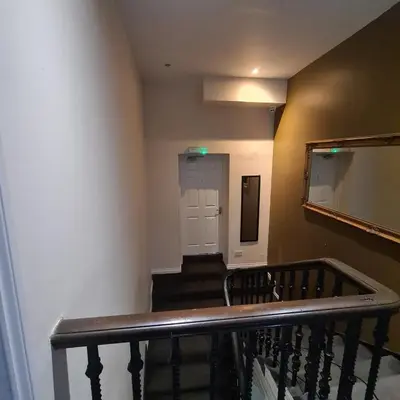 a hallway with a staircase with a door and a mirror at The Beath Inn in Cowdenbeath