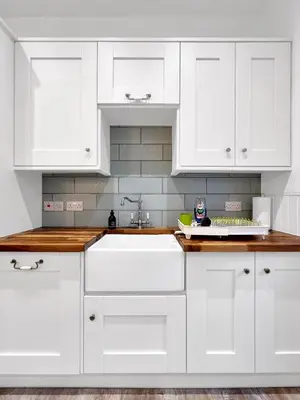 a white kitchen with white cabinets and a sink at No.3 The Villa in Oban