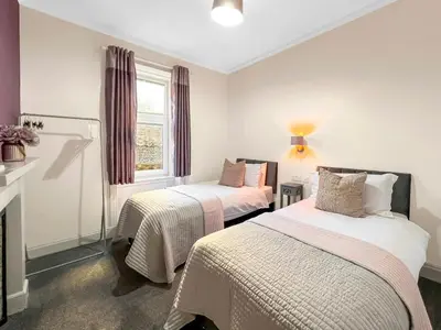 two beds in a room with a window at No.3 The Villa in Oban