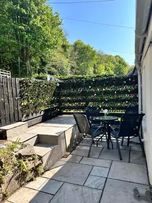 a patio with a table and chairs in front of a hedge at No.3 The Villa in Oban