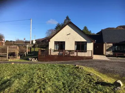 a white house with a porch and a yard at Snowberry Cottage No 2 in Onich