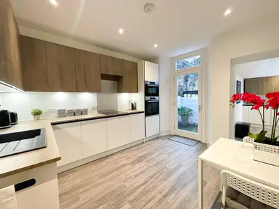 a kitchen with white cabinets and a wooden floor at 2Bed, Private Garden & Fireplace, Near Water of Leith in Edinburgh