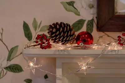 a table with christmas decorations on top of a fireplace at Stables Cottage in Stranraer