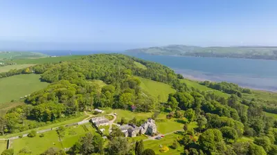an aerial view of a mansion on a hill next to a lake at Stables Cottage in Stranraer