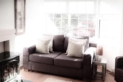 a couch with pillows in a living room with a window at Best location in town, it is all on the doorstep. in Ayr