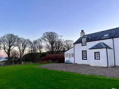 a white house with a grass yard in front of it at Rural Farmhouse on Kintyre, West Coast hidden gem in Kildalloig