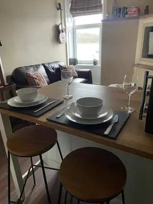 a kitchen with a table with plates and wine glasses at An Cuilidh in Port Bannatyne