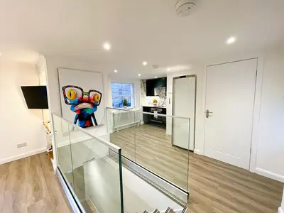 a staircase with a glass railing in a house at Stunning Loft Apartment South Queensferry High St Bridge Views! in Queensferry