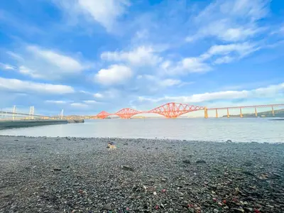 a red bridge over the water with a bridge in the background at Stunning Loft Apartment South Queensferry High St Bridge Views! in Queensferry