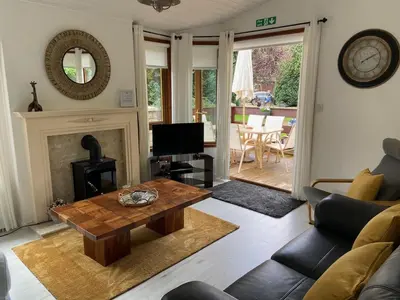 a living room with a table and a fireplace at Walled Garden Lodges Loch Lomond in Balloch