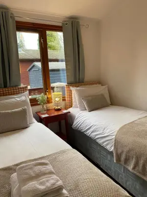 two beds in a room with a window at Walled Garden Lodges Loch Lomond in Balloch