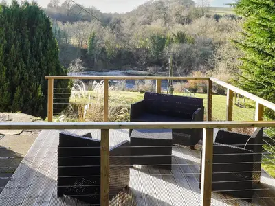 a wooden deck with a bench on top of it at Riverside Cottage in Larkhall