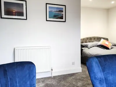 a bedroom with a bed and two blue chairs at Riverside Cottage in Larkhall