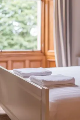 two towels on a bed in front of a window at Beautiful 2 Bed 2 Bath Flat overlooking Meadows Park in Edinburgh