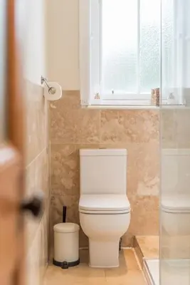 a bathroom with a white toilet and a window at Beautiful 2 Bed 2 Bath Flat overlooking Meadows Park in Edinburgh