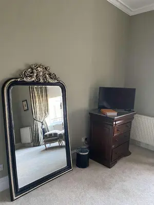 a mirror in a room with a dresser and a chair at West End Townhouse in Edinburgh