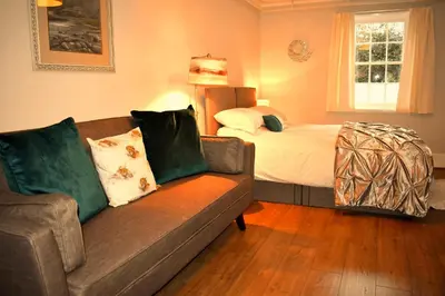 a living room with a couch and a bed at Corrie Apartment, Kinlochlaich House in Appin