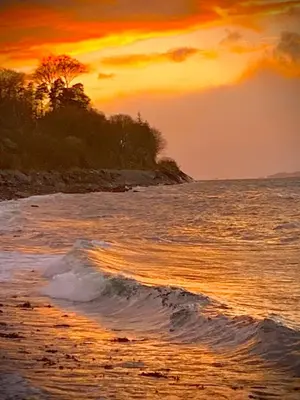 a sunset on a beach with the ocean at Corrie Apartment, Kinlochlaich House in Appin