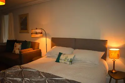 a bedroom with a bed with a pillow and a lamp at Corrie Apartment, Kinlochlaich House in Appin