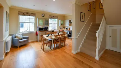 a kitchen and living room with a staircase and a table at Garden Cottage in Stranraer