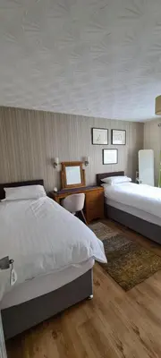 a bedroom with two beds and a desk at Lowefield B&B in Plean