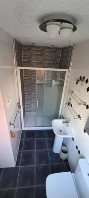 a bathroom with a shower and a toilet and a sink at Lowefield B&B in Plean