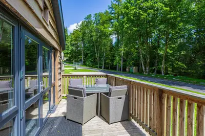 a wooden porch with a table and chairs on it at Squirrel Lodge 40 with Hot Tub in Newton Stewart