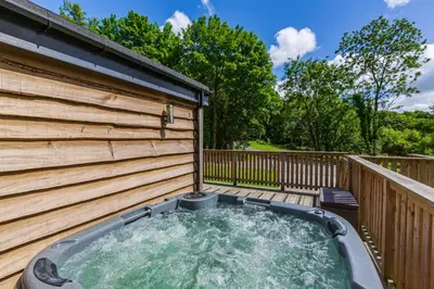 a hot tub on a deck next to a fence at Squirrel Lodge 40 with Hot Tub in Newton Stewart