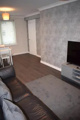 a living room with a couch and a flat screen tv at Kelpies Serviced Apartments- Cromwell Apt in Falkirk
