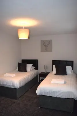 a bedroom with two beds and a light on the ceiling at Kelpies Serviced Apartments- Cromwell Apt in Falkirk
