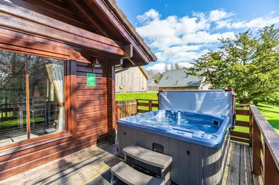 a hot tub on a deck next to a building at Lady Galloway 27 with Hot Tub in Newton Stewart