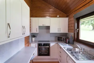 a kitchen with white cabinets and a sink and a window at Lady Galloway 29 with Hot Tub in Newton Stewart