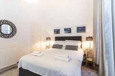 a bedroom with a white bed with two towels on it at GLASGOW WEST END 5 MIN WALK TO SECC AND HYDRO in Glasgow