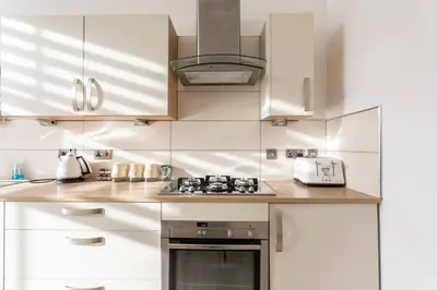 a kitchen with white cabinets and a stove top oven at GLASGOW WEST END 5 MIN WALK TO SECC AND HYDRO in Glasgow