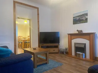 a living room with a television and a fireplace at Cosy detached house in central location in Oban