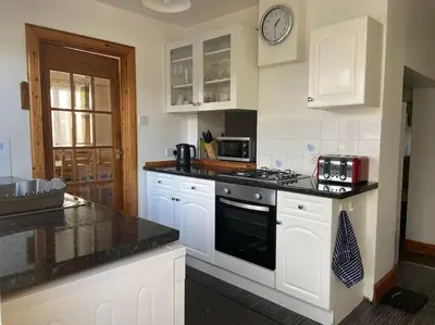 a kitchen with white cabinets and a black stove top oven at Cosy detached house in central location in Oban