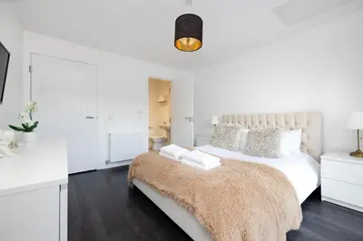a white bedroom with a large bed with a brown blanket at Stylish 3BR Home with Garden & Free Parking - Near O2 Academy & City Centre in Glasgow