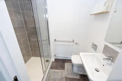 a bathroom with a shower and a toilet and a sink at Stylish 3BR Home with Garden & Free Parking - Near O2 Academy & City Centre in Glasgow