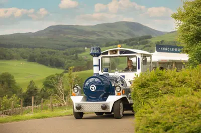 a blue and white train driving down a road at Crieff Hydro Self Catering in Crieff