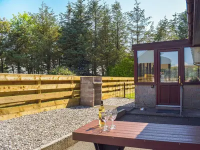 a wooden table with two wine glasses on top of it at Lowesmuir Cottage in Cumnock