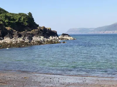 a beach with a rocky shore and the ocean at High Clachan Farmhouse in Stranraer