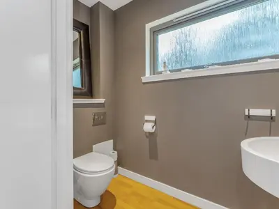 a bathroom with a toilet and a sink and a window at Cheerful Stays: 4 Bedroom Cottage in Arrochar in Arrochar