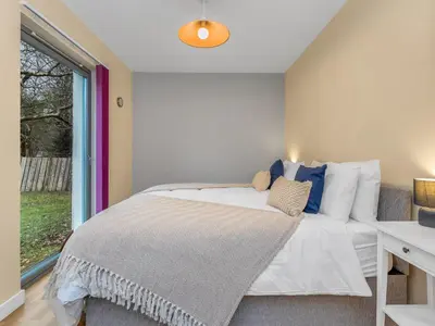 a bedroom with a large bed and a window at Cheerful Stays: 4 Bedroom Cottage in Arrochar in Arrochar