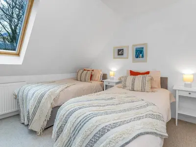 two beds in a room with white walls and a window at Cheerful Stays: 4 Bedroom Cottage in Arrochar in Arrochar